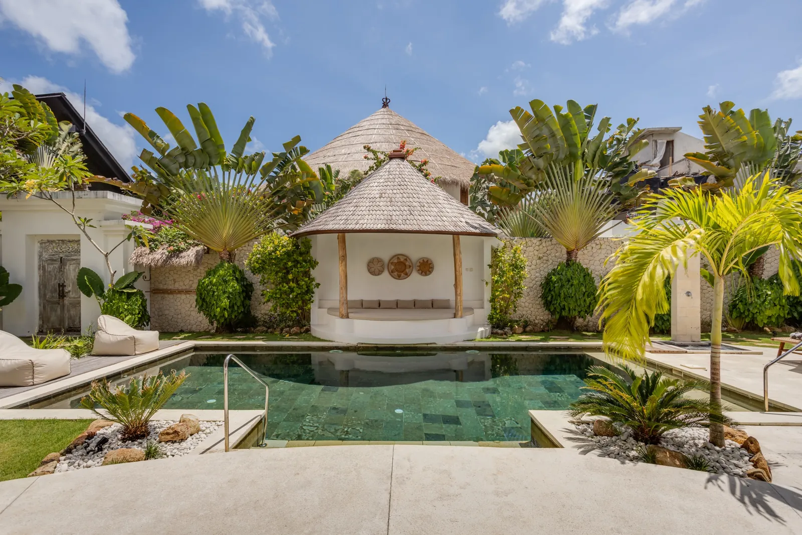 The private pool at Madu Bungalow Bingin with thatched gazebo and sun loungers, midday